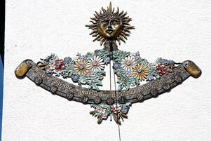 Pieza decorativa para colgar en la pared con motivos de sol y diseños florales.