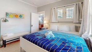 A hotel room with a bed, a bench, a painting, and a window with curtains. - Historic Bungalow w/porch, King1bd/1ba, Recently Renovated (Albuquerque)