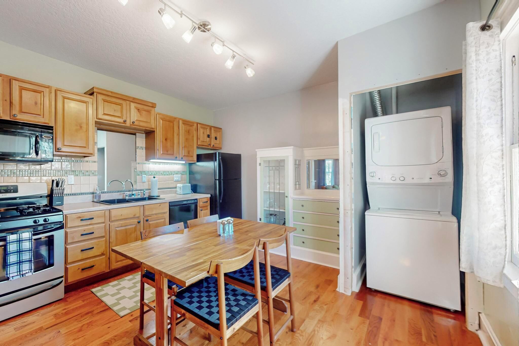 A kitchen with wooden cabinets, a stainless steel refrigerator, a microwave, and a stove.