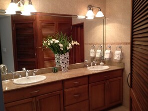 Un baño con dos lavamanos, un espejo y un florero con flores.
