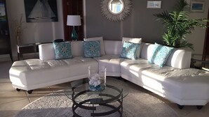 A modern living room with a white sectional sofa, a glass coffee table, and decorative pillows. - Oceanfront Spectacular Penthouse W/Spacious Rooftop Terrace, Cupecoy Beach (Cupecoy)