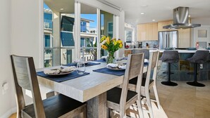 A modern kitchen with a large island, stainless steel appliances, and a view of the city. - Rockaway Oceanfront 2 | Lg Terrace- 4BR (San Diego)