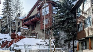 A winter scene with a stone staircase leading to a hot tub area, surrounded by wicker furniture and snow-covered steps. - Immediate ⛷ In/out,  🏔 views,  walk 2 village, PERFECT location, OFP, Pool&HotT (Avon)