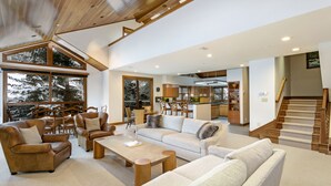 A spacious living area with a high ceiling, large windows, and a staircase leading to an upper level. - Immediate ⛷ In/out,  🏔 views,  walk 2 village, PERFECT location, OFP, Pool&HotT (Avon)
