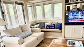 A living room with a beige sofa, a wooden coffee table, and a television displaying a news channel. - Sunny St Andrews Common, Palmetto Dunes, 1st Floor 2Bed/2Ba, 2 Bikes, Near Pool (Hilton Head Island)