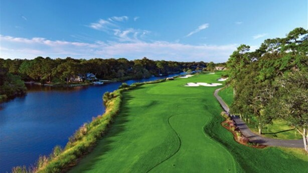 A golf course with a water body on one side, a well-maintained green, and a path along the edge. - Sunny St Andrews Common, Palmetto Dunes, 1st Floor 2Bed/2Ba, 2 Bikes, Near Pool (Hilton Head Island)
