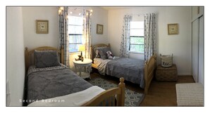 A second bedroom with two single beds, a small round table, and a window with curtains. - Tropical painter and writer retreat (Jensen Beach)