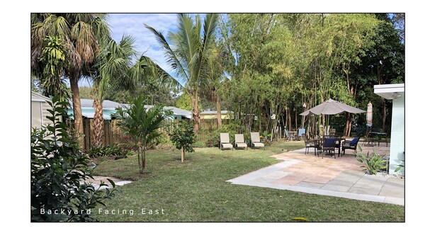 A backyard with a patio, lounge chairs, and a dining area. - Tropical painter and writer retreat (Jensen Beach)