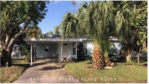 A single-story house with a front porch, a small garden, and a pathway leading to the entrance. - Tropical painter and writer retreat (Jensen Beach)