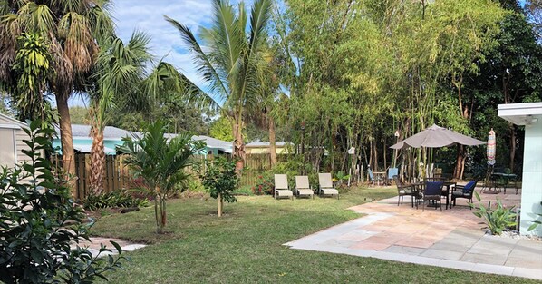 A backyard with a patio, lounge chairs, and a dining area.