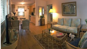 A cozy living room with a sofa, chairs, a coffee table, and a dining area with a table and chairs. - Tropical painter and writer retreat (Jensen Beach)