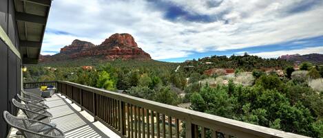 A balcony with a view of red rock formations and green trees.