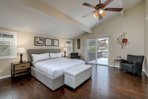 Une chambre avec un grand lit, un ventilateur de plafond, un balcon et une chaise.