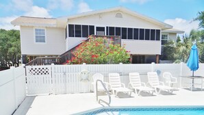 A pool area with white lounge chairs and a blue umbrella. - Spacious pool home on corner lot close to beach boardwalk. Gulf view and clean! (St. George Island)