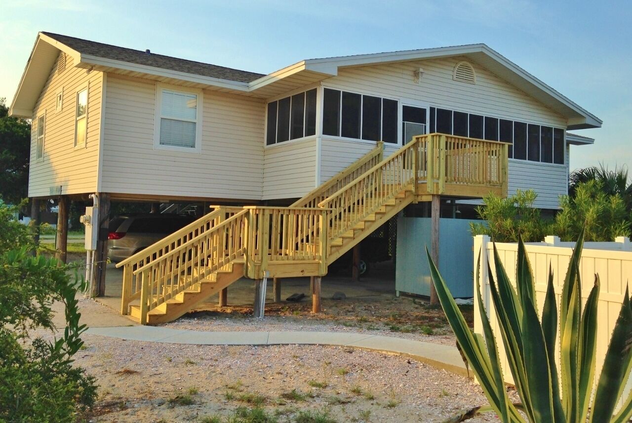 A two-story house with a wooden staircase leading to a balcony.