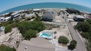An aerial view of a coastal residential area with houses, a swimming pool, and a beach. - Spacious pool home on corner lot close to beach boardwalk. Gulf view and clean! (St. George Island)