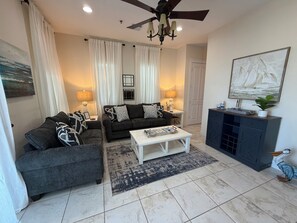 A living room with a sofa, armchair, coffee table, and a cabinet.