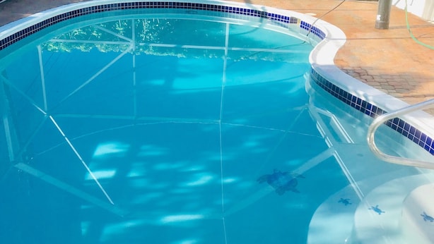 Une piscine d’un bleu éclatant, bordée de carreaux et dotée d’une échelle visible.