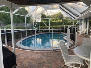 A covered outdoor swimming pool with a glass roof, surrounded by a brick patio and furnished with lounge chairs and a table. - Paradise at Its' Best. Your Home Away From Home....Pets welcome & Tesla Charger (Tequesta)