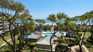 Un resort con piscina, vista a la playa y varias construcciones.