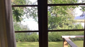 Ikkunasta avautuu näkymä vehreälle alueelle ja puukannelle.