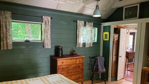 Un dormitorio con cama, cómoda, silla y una puerta que da a otra habitación.