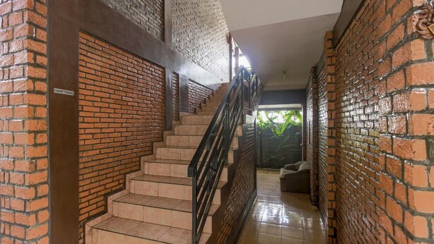 A staircase with a brick wall on one side and a tiled floor. - RedDoorz Plus @ Ampera Raya (Jakarta)