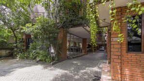 A courtyard with brick buildings, a paved walkway, and lush greenery. - RedDoorz Plus @ Ampera Raya (Jakarta)