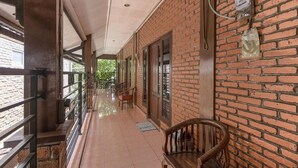A covered corridor with brick walls, wooden benches, and a tiled floor. - RedDoorz Plus @ Ampera Raya (Jakarta)