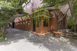 Un callejón de ladrillo estrecho con un pequeño edificio de ladrillo, una mesa y sillas afuera.