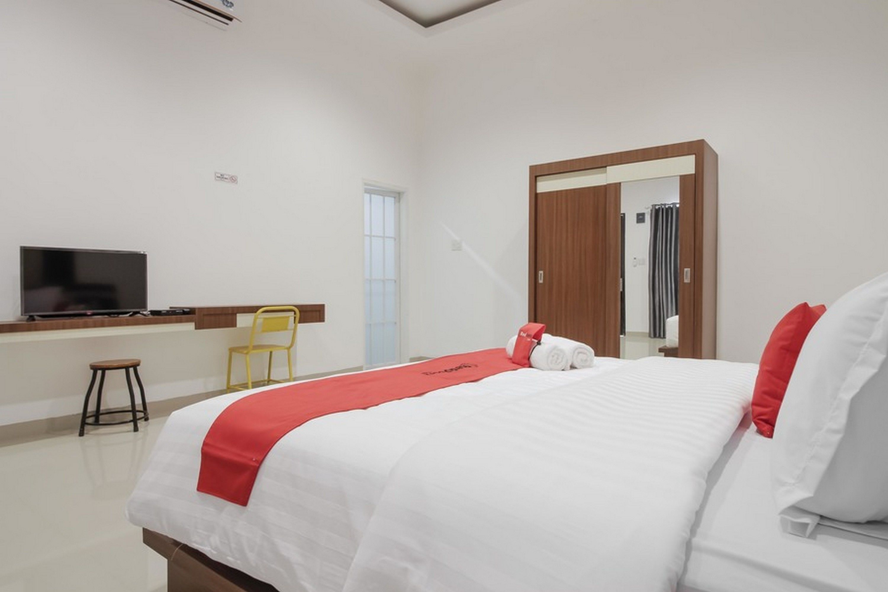 Una habitación de hotel con una cama, televisor, escritorio y una silla.