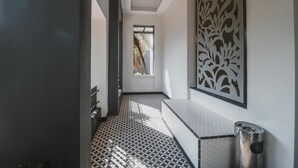 Un couloir doté d’un revêtement de sol à motifs, d’un banc, d’une poubelle et d’un panneau décoratif mural.