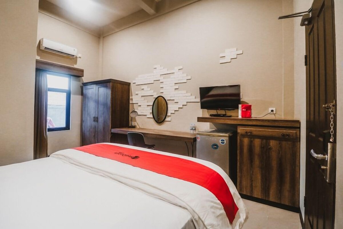 Une chambre d’hôtel équipée d’un lit, d’un bureau, d’une télévision et d’une armoire.