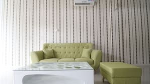 A room with a green sofa, a glass coffee table, and a matching ottoman. - RedDoorz @ Baloi Batam (Batam)