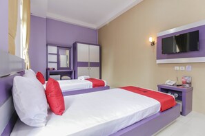 Ein Hotelzimmer mit zwei Betten, einem Fernseher, einem Spiegel, einem Kleiderschrank und einem Nachttisch mit Telefon und Lampe.