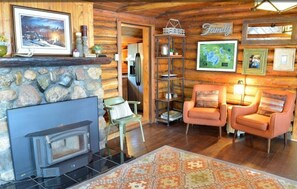 Cozy cabin interior with a stone fireplace, comfortable seating area, and decorative rug.