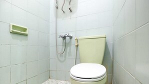 Een compacte, afgesloten badkamer met toilet, douche en handzeepdispenser.
