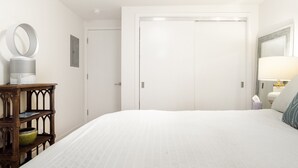 Ein Hotelzimmer mit einem großen Bett, einem Nachttisch mit Lampe, einem Spiegel und einem Kleiderschrank.