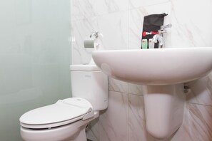 A bathroom with a white toilet, a white sink, and a toilet paper holder.