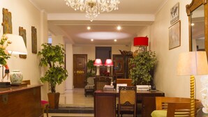 A well-lit room with a chandelier, wooden furniture, and potted plants. - RedDoorz near Gasibu Bandung (Bandung)