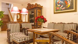 A living room with houndstooth patterned furniture, a wooden coffee table, and a painting of koi fish. - RedDoorz near Gasibu Bandung (Bandung)