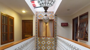 A corridor with a white balustrade, patterned wall tiles, and wooden doors. - RedDoorz near Gasibu Bandung (Bandung)