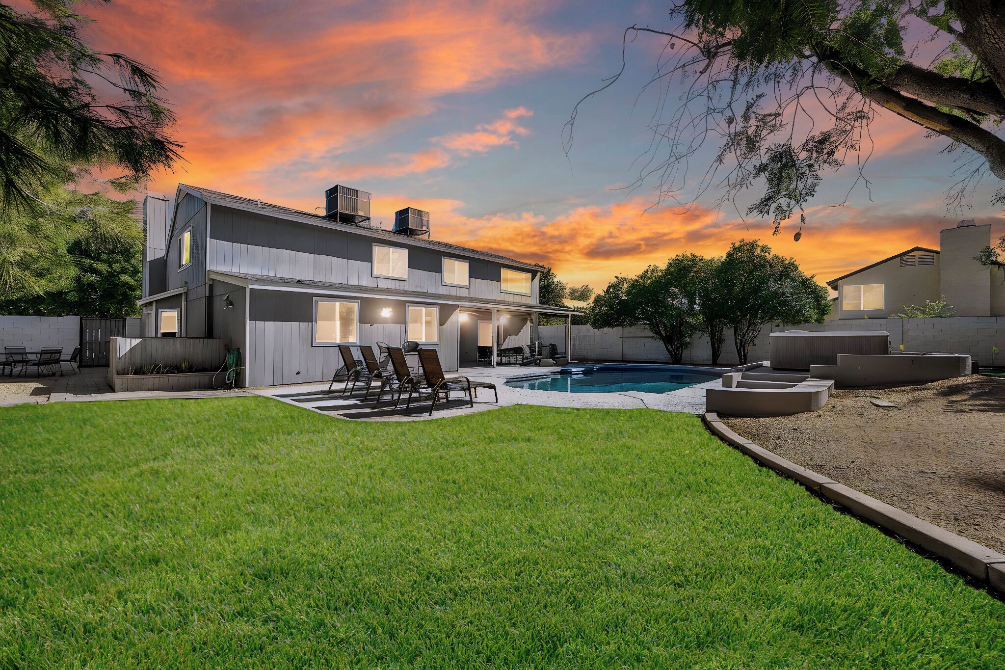 A modern two-story house with a swimming pool, outdoor seating, and a well-maintained lawn.