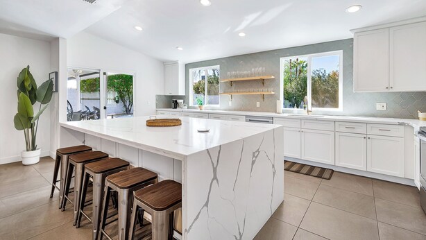 Cozinha moderna com uma ilha grande, banquetas e vista para o exterior.