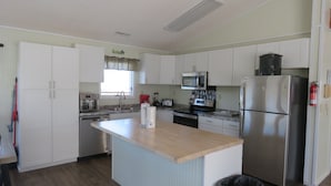 Una cocina moderna con armarios blancos, una isla central, electrodomésticos de acero inoxidable y un ventanal con vistas.