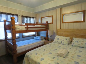 A bunk bed room with a wooden headboard, a bedside table with a lamp, and a bed with a floral bedspread. - Elevator,Pool,Theater Rm,Pool table,huge master shower,great oceanviews (Nags Head)