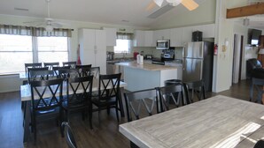 Una cocina amplia con armarios blancos, una isla central y un comedor con sillas de madera y una mesa.