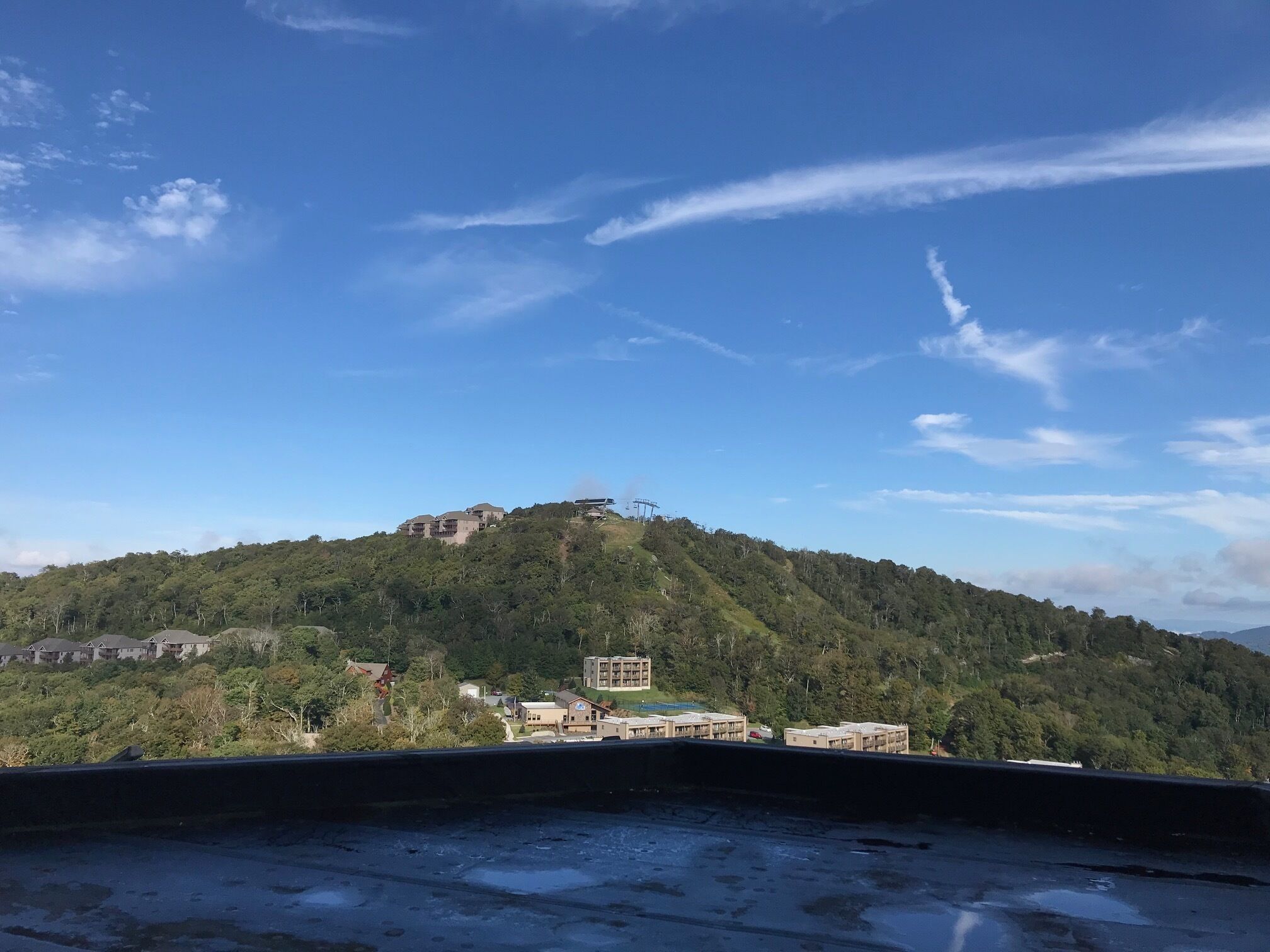 Une vue d’une colline parsemée de bâtiments, dont une grande construction surmontée d’un dôme et plusieurs bâtiments plus petits.