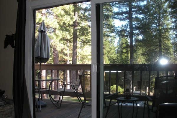Outdoor deck with seating and gas grill overlooking greenbelt