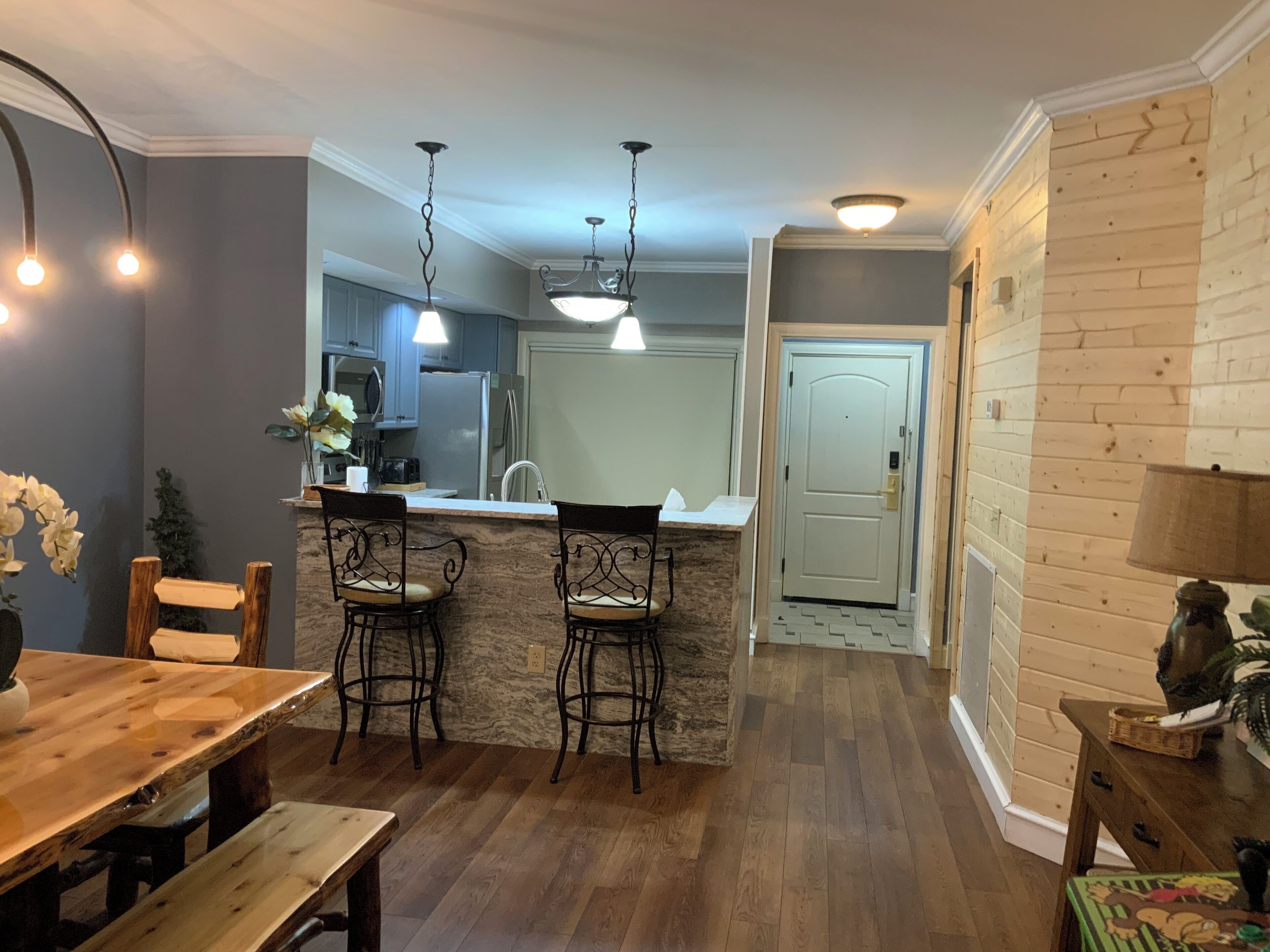 Una cocina moderna con una isla central, taburetes de bar e iluminación colgante.